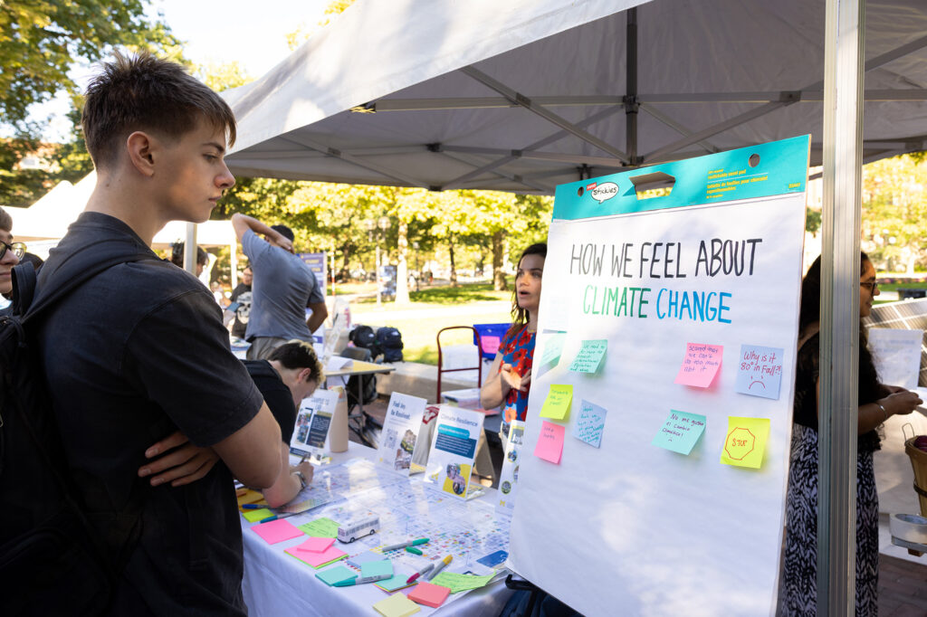 A student looks at a large pad of paper with sticky notes answering the question how do we feel about climate change