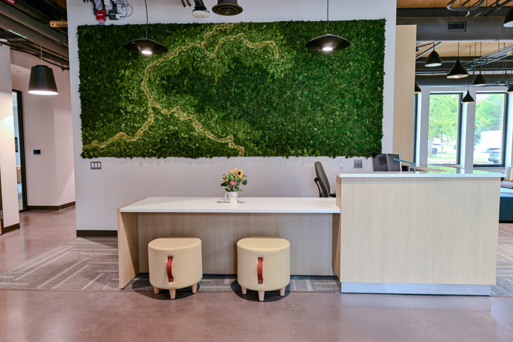 A desk with two chairs and a large piece of green art hanging behind it