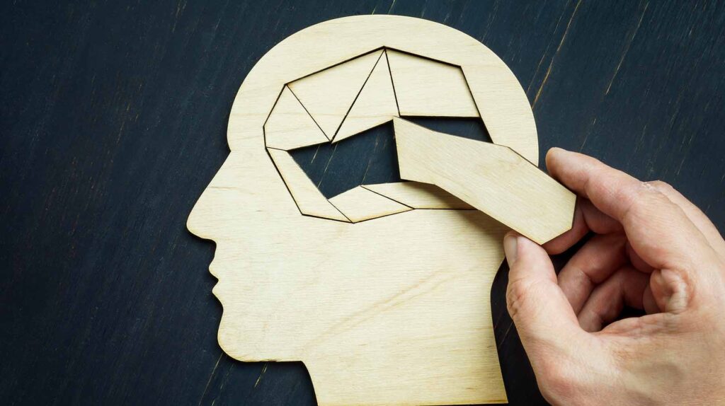 Memory loss and problems with brain. The hand puts the last piece of the puzzle. Image credit: Adobe Stock