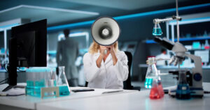 Scientist in lab speaks into megaphone. iStock.