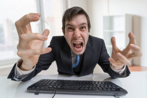 Angry caucasian guy wearing a tie rages at his keyboard.