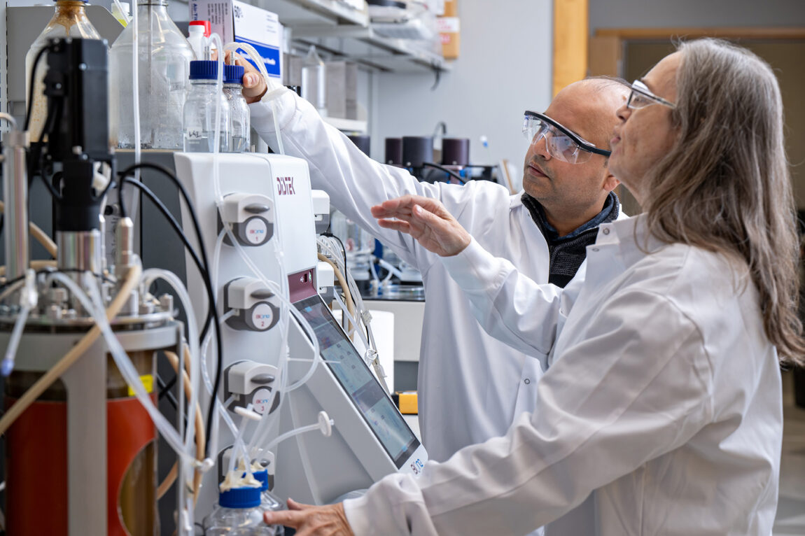 Two researchers in white lab coats perform an experiment