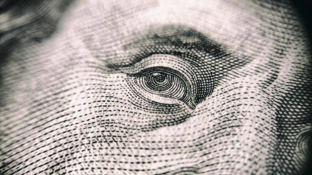 Close-up of a finely detailed black-and-white engraving showing an eye from U.S. currency, emphasizing the intricate lines and textures of the print. Image credit: Vladislav Reshetnyak, Pexels