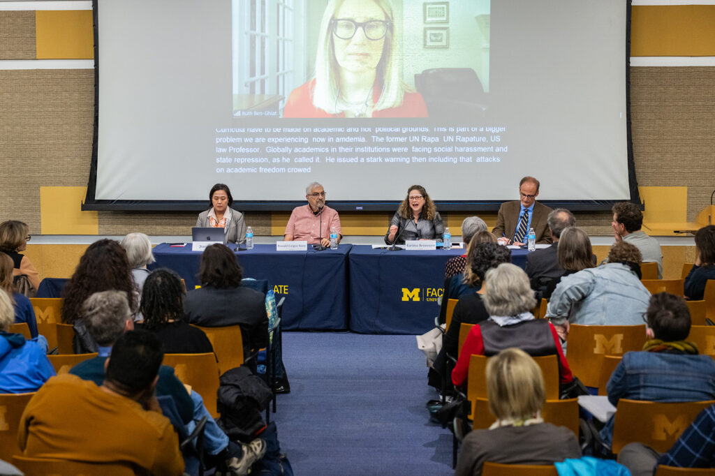 Ruth Ben-Ghia shown on a big screen at the 35th DMN lecture. Also pictured are panelists Jean Hong, Ronald Grigor Suny and Karima Bennoune — and the panel moderator Faculty Senate Chair Derek Peterson.