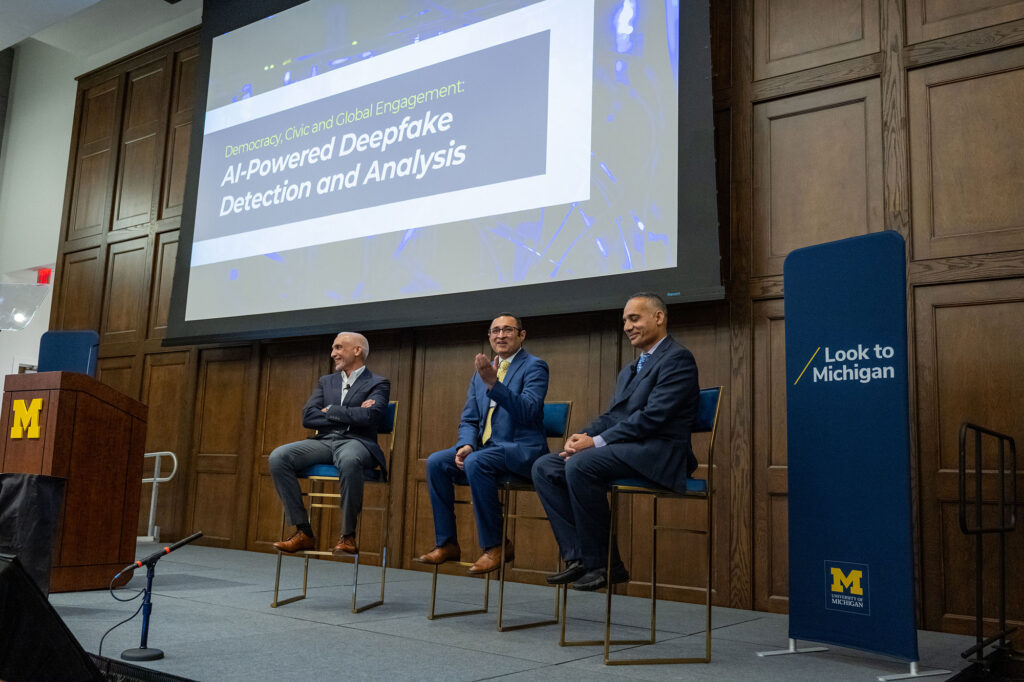 Three men on stage talking.
