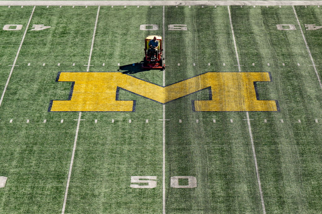 A person on a groomer near midfield of Michigan Stadium