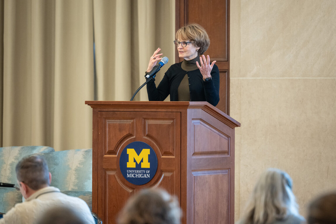 A woman stands at a lectern and addresses a crowd