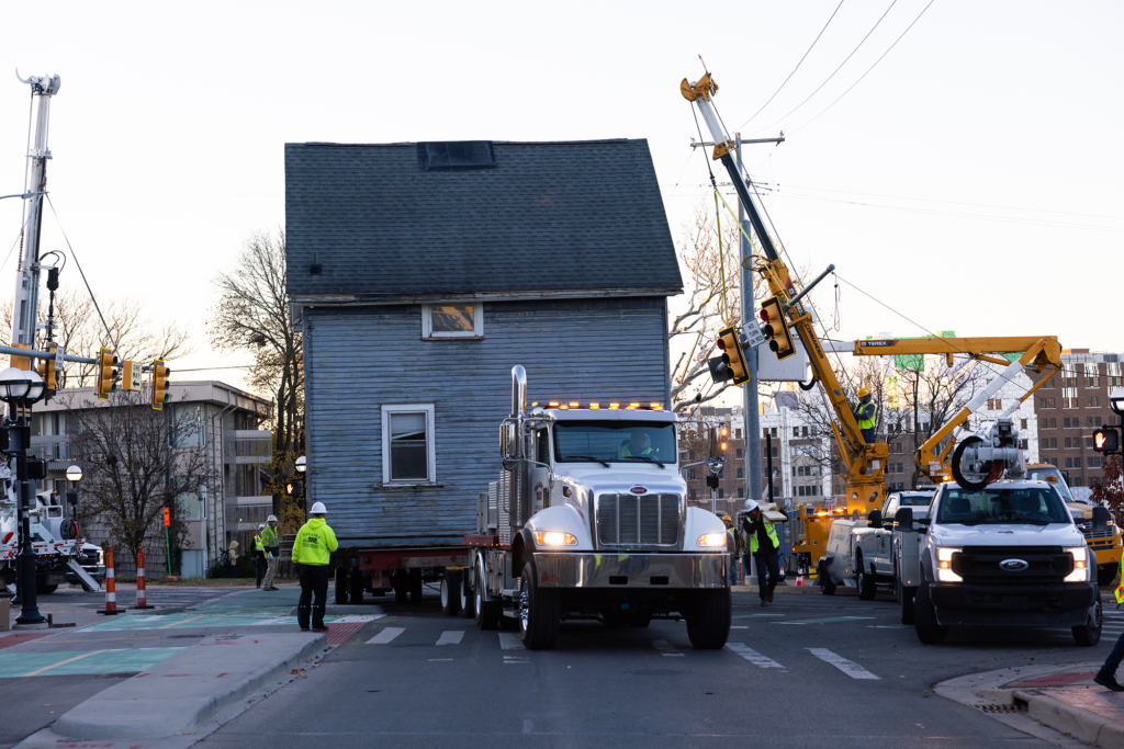 A house is hauled down a street by a trailer
