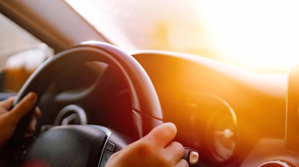 Close up of driver hands driving in road trip. Image credit: Adobe Stock