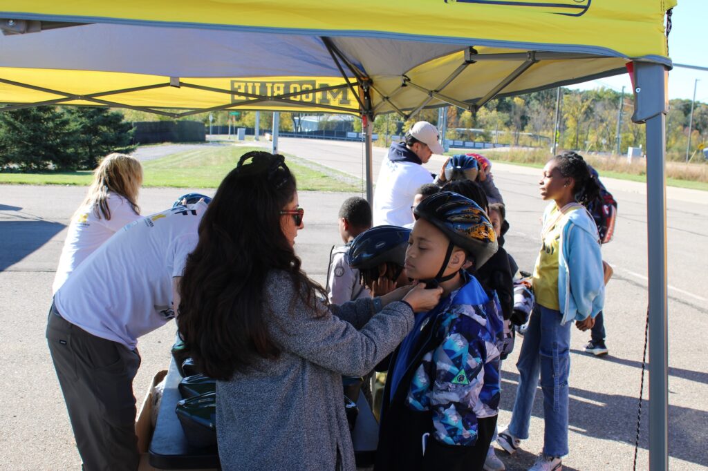 U-M staff are distributing helmets to kids and explaining how to adjust them. Image credit: Juan Ochoa