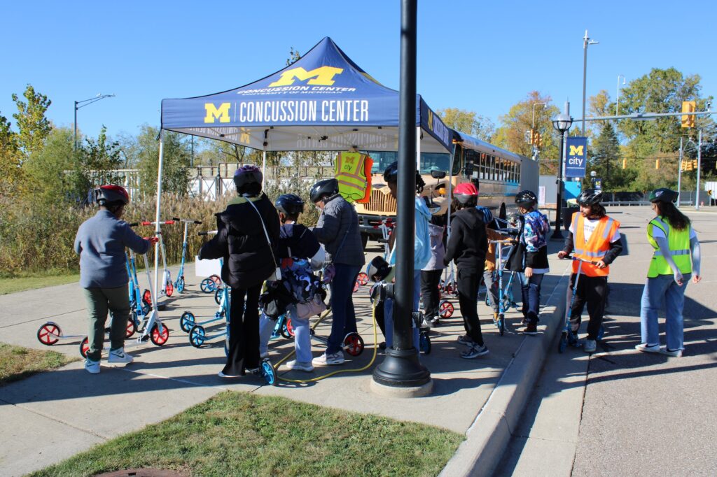 Kids are picking up scooters and preparing to start riding as student volunteer Dylan Hogan explains safety guidelines. Image credit: Juan Ochoa