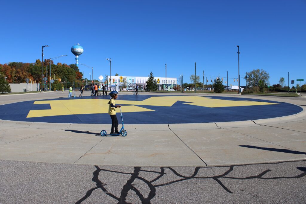 Participants riding a scooter around the U-M logo. Image credit: Juan Ochoa