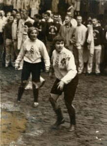 Black and white image, circa 1959, of college girls competing in a mud bowl.
