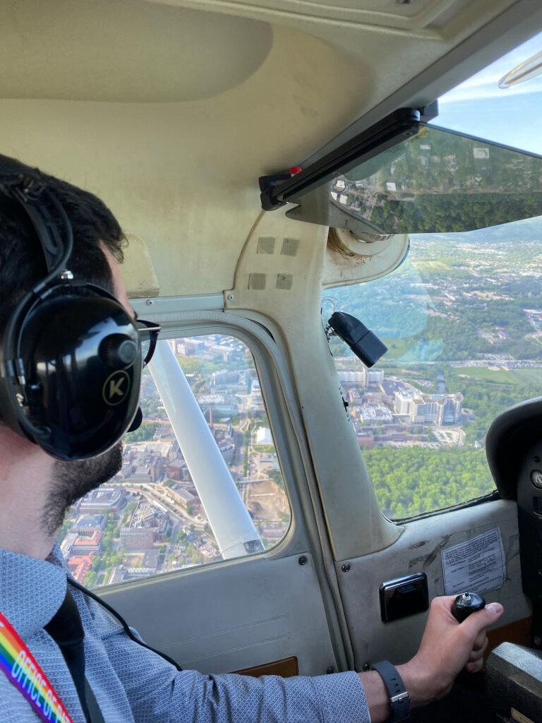 A man flying a plane looks at buildings below on the ground
