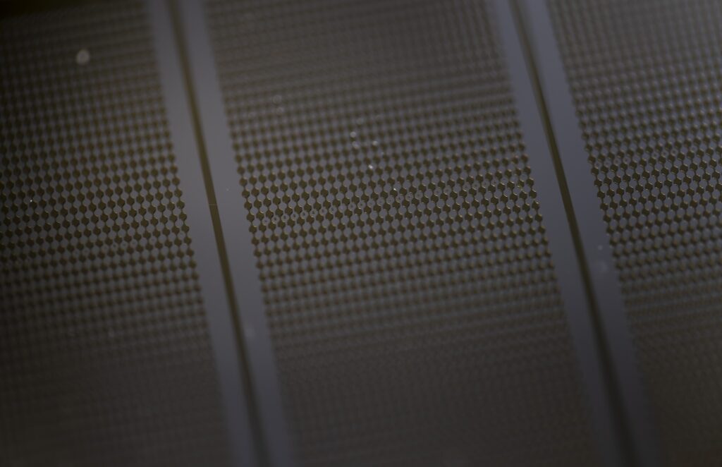 The microwell structure in the GlioExoChip designed at U-M, and used by the U-M/Northwestern team to discover whether a brain cancer treatment was working, is shown in close-up. The half-a-millimeter-wide wells are coated with a molecule that grabs onto a lipid, or fat molecule, that appears on the surface of extracellular vesicles sent out by glioblastoma tumor cells. Image credit: Jeremy Little/Michigan Engineering