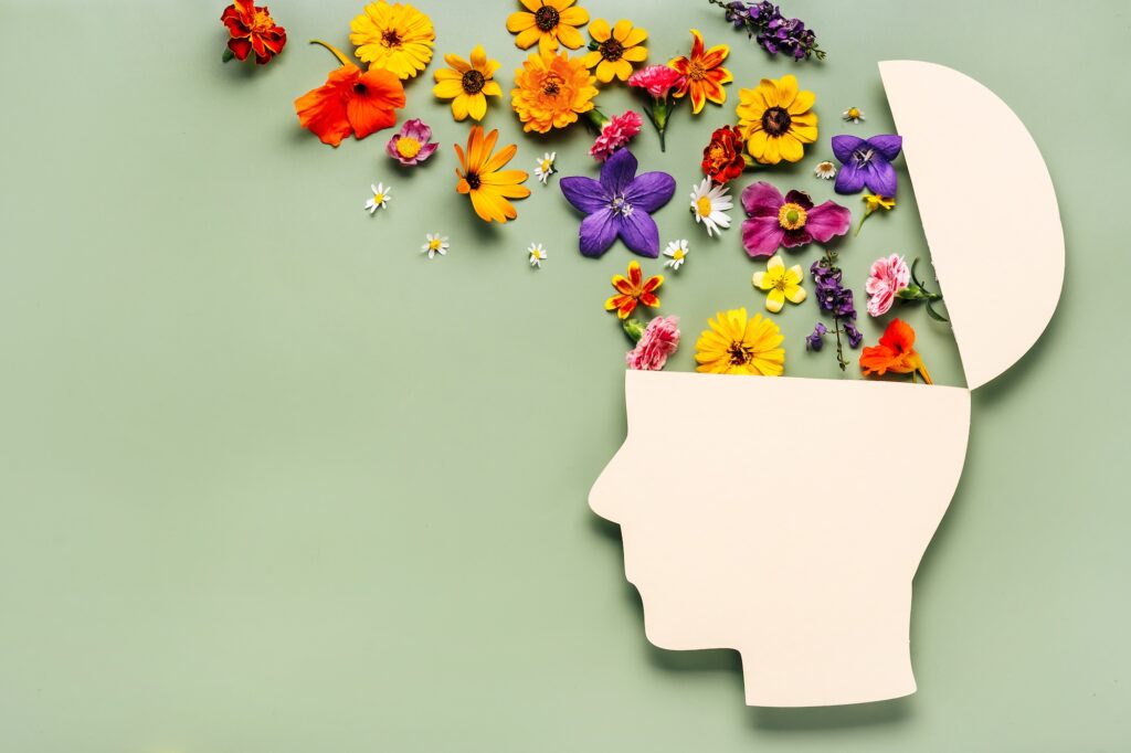 World Mental Health Day concept. Human head symbol of paper and flowers on blue background. Image credit: Katecat, Adobe Stock