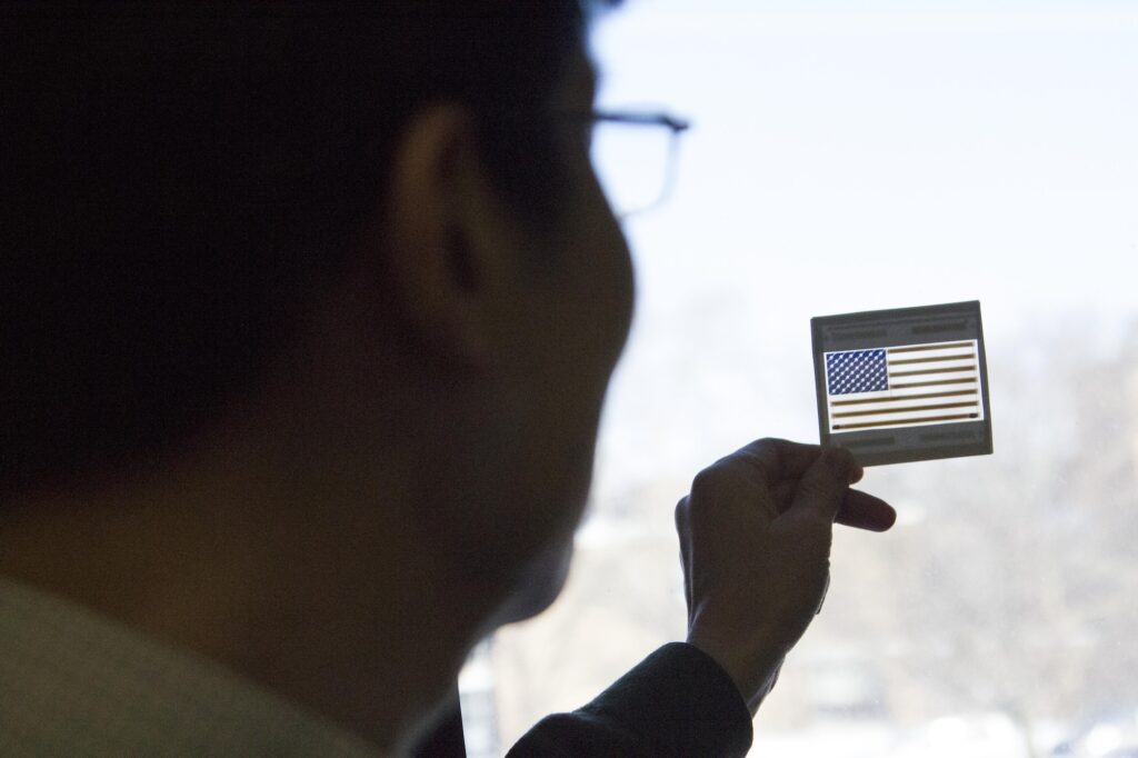 Guo demonstrates a small colored solar panel styled as an American flag in 2014. Image credit: Robert Coelius, Michigan Engineering