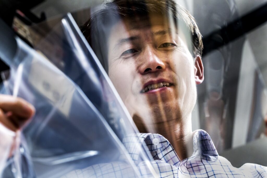 Jay Guo demonstrates a flexible "stainless silver" conductive coating in his lab in 2017. The coating combines silver and aluminum for a tarnish-resistant conductive surface. Image credit: Joseph Xu, Michigan Engineering