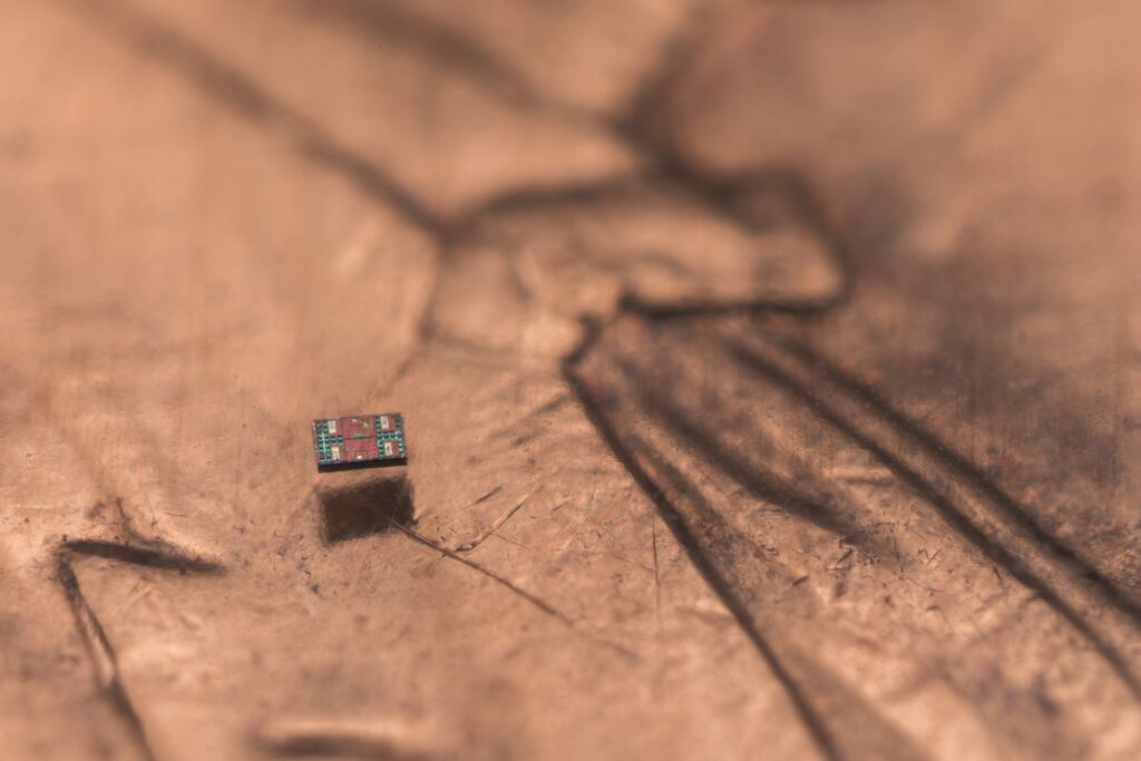 The M3 (Michigan Micro Mote) computer alone, shown floating above what appears to be Lincoln's shoulder for scale. Photo taken at the Michigan Integrated Circuits Laboratory. Image credit: Michael Simari