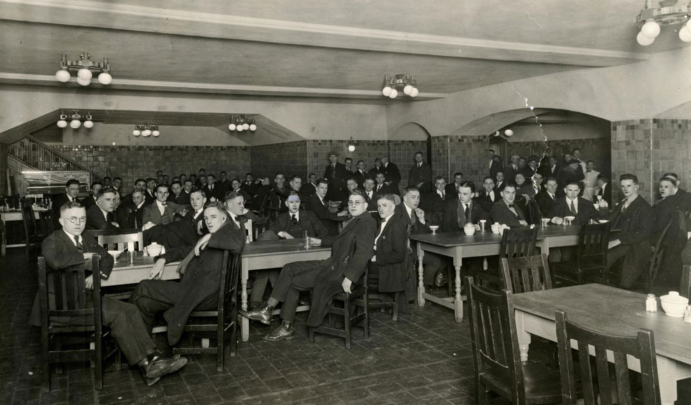 University of Michigan men in the U-M Union tap room. Big group at tables wth arched ceiling.