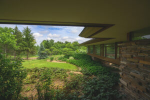 A view of nature from the vantage point of a Frank Lloyd Wright-inspired house set among rolling hills and trees.
