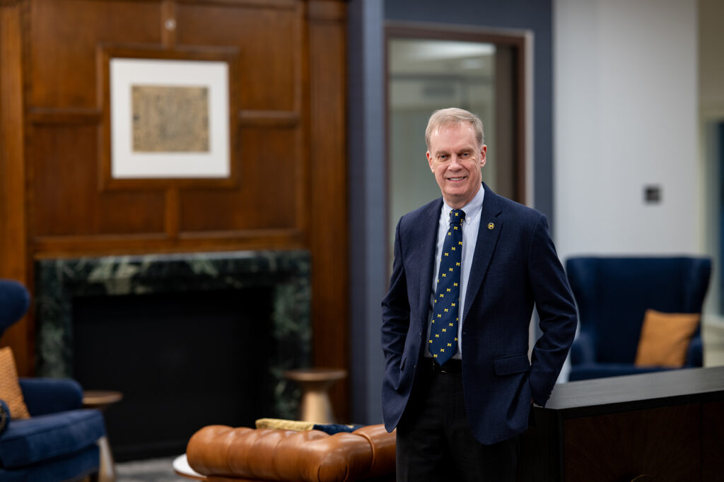 Kent Syverud stands in a room with furniture and a fireplace