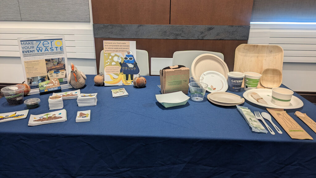 Plates, utensils and stickers all encouraging responsible environmental actions are set up on a table with a dark blue tablecloth