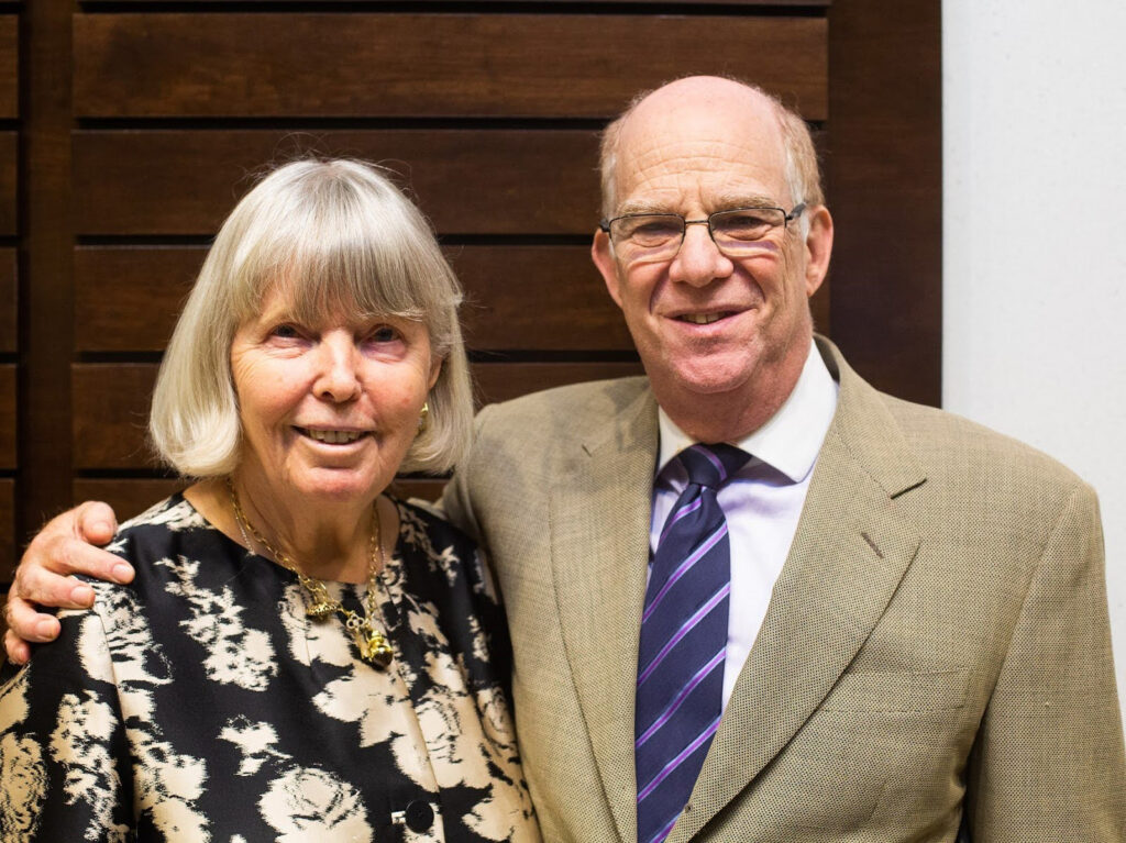 A woman and a man stand side by side smiling