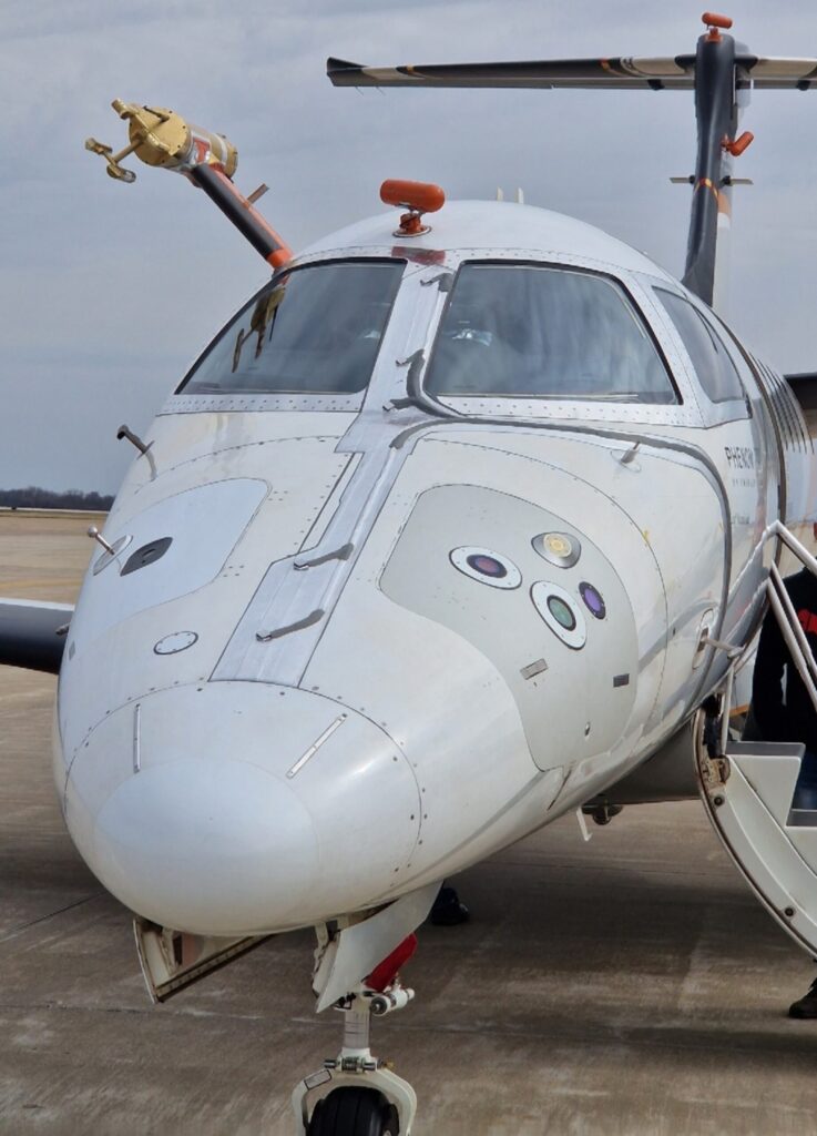 Renno's optical and microwave sensors for detecting ice and freezing rain were embedded into the nose of a small business jet. The green circle on the right is the optical sensor, and the yellow circle on the right side is the microwave sensor. The performance of the sensors was compared to that of a sensitive, laboratory-grade instrument; see the gold cylinder above the cockpit, to the left. Image credit: SENS4ICE, copyright AeroTex UK LLP. Used with permission.