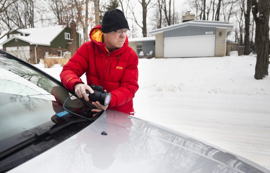Nilton Renno mounts the infrared sensor onto his car, to test how well it performs on a snow-covered, residential road. Image credit: Jeremy Little, Michigan Engineering.