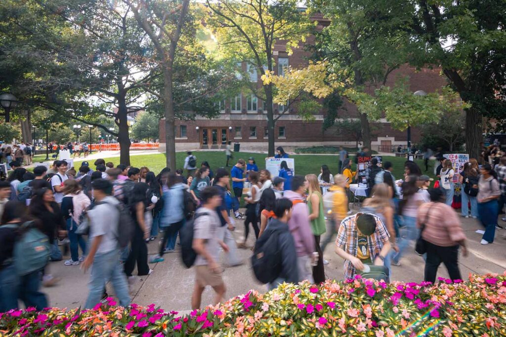 A long exposure photo of a large crowd of students walking along a busy sidewalk at Festifall 2025 in front of Hill Auditorium at U-M. Image credit: Connor Titsworth, Michigan Commons